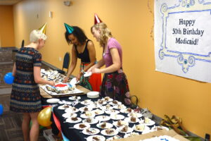 Some Appleseeders cutting and dishing up cake for the Medicaid birthday party at the Center For People In Need.